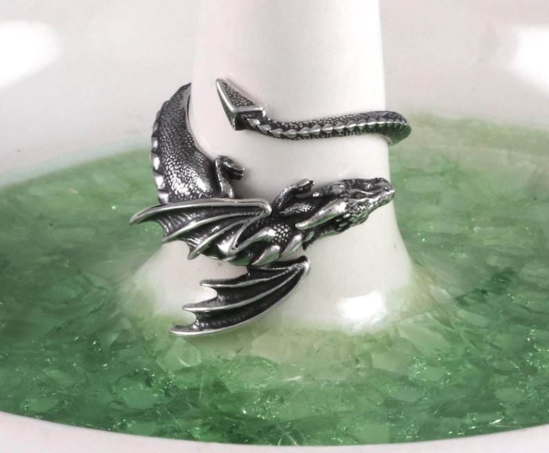 May include: A silver dragon ring with a detailed design. The dragon's tail wraps around the ring band.