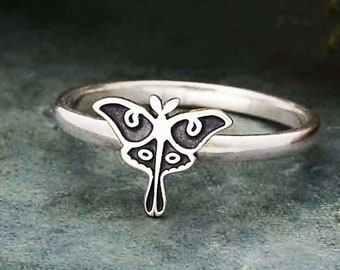 May include: A silver ring with a black butterfly design. The butterfly has intricate details and a delicate silhouette.