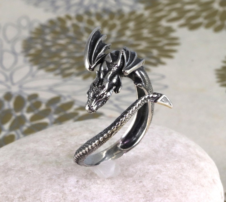 May include: A silver dragon ring with a detailed design. The dragon is curled around the ring band, with its wings spread out. The ring is made of sterling silver and is a great gift for anyone who loves dragons.