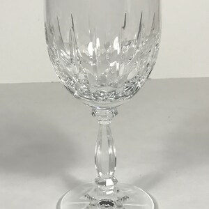 May include: A clear glass wine glass with a cut crystal design. The glass has a tall stem and a wide bowl.