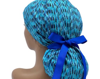 May include: A blue and black patterned surgical scrub hat with a blue ribbon tied in a bow at the back.