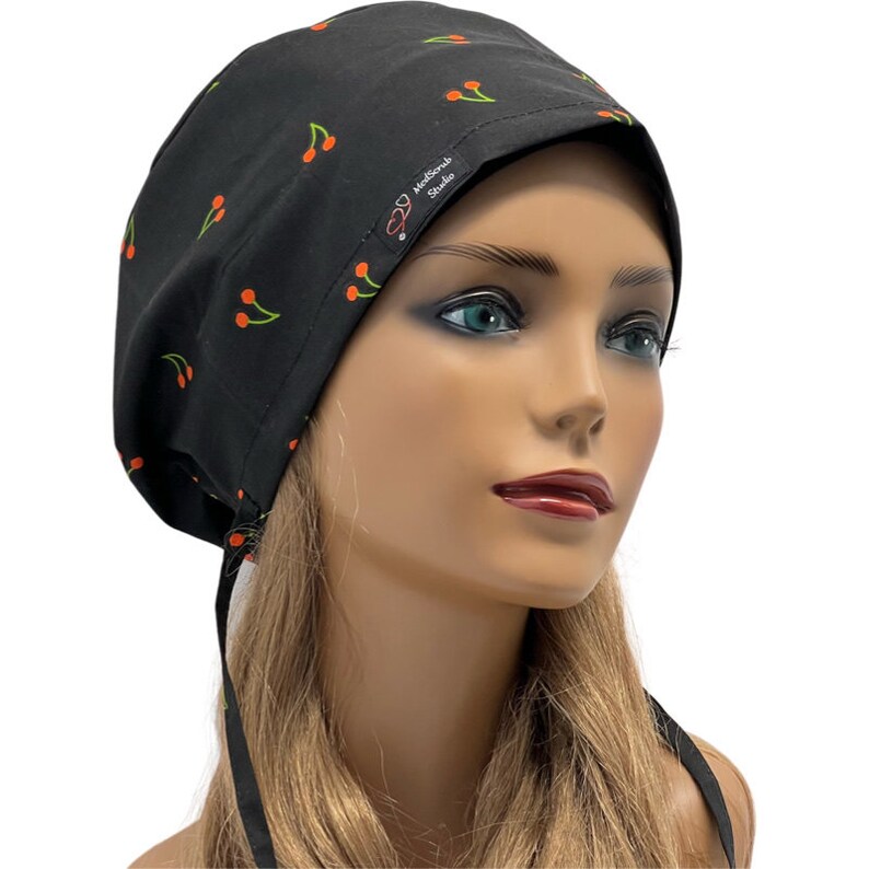 May include: Black scrub hat with a cherry print and the text "MedScrub Studio" on the side. The hat has a tie at the back.