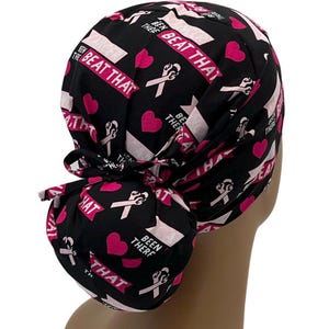 May include: Black and pink patterned surgical scrub hat with a pink ribbon and the text "Beat That" and "Been There".