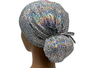 May include: A silver and iridescent scrub hat with a tie at the back. The hat has a geometric pattern.