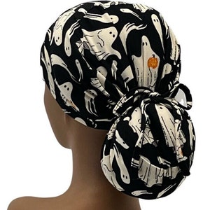 May include: Black and white scrub hat with a ghost pattern. The hat has a ponytail opening and a tie at the back.