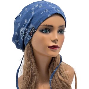 Pode incluir: Um gorro azul com um padr&atilde;o de dente-de-le&atilde;o branco. O chap&eacute;u tem um fecho de la&ccedil;o e uma pequena etiqueta com texto. O chap&eacute;u de tecido macio foi concebido para ser usado na cabe&ccedil;a.