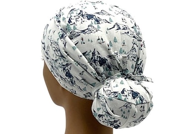 May include: White scrub hat with a blue and green mountain and pine tree pattern. The hat has a ponytail opening in the back.