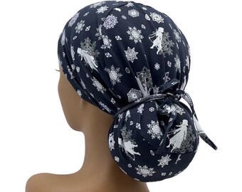 Könnte beinhalten: Eine marineblaue OP-Haube mit einem weißen Schneeflocken- und Charakterdruck. Die Haube ist hinten mit einer passenden Stoffschleife gebunden. Sie dient dazu, das Haar zu bedecken.