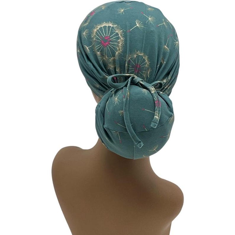 Peut inclure: Couvre-chef de couleur teal avec un motif de pissenlit dor&eacute; et rose. Le tissu est fronc&eacute; &agrave; l'arri&egrave;re et nou&eacute;. Le couvre-chef est con&ccedil;u pour &ecirc;tre port&eacute; sur la t&ecirc;te.