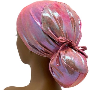 May include: A pink iridescent surgical scrub hat with a bun cover. The hat is tied at the back with a bow.