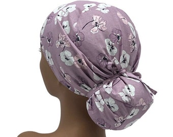 Peut inclure: Un bonnet de travail violet avec un motif floral blanc. Le bonnet a un lien pour chignon à l'arrière.