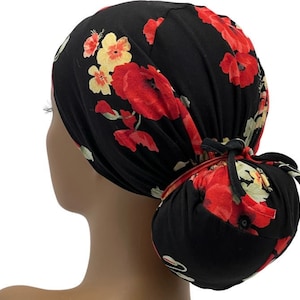May include: Black scrub hat with a floral print featuring red and yellow flowers. The hat has a bun covering and a tie at the back.