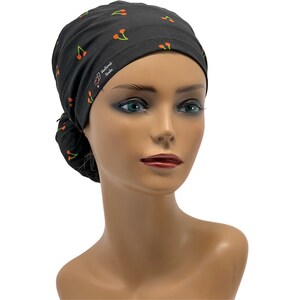 May include: Black surgical scrub hat with a cherry print. The hat has a tie on the back and the text "SD Heartbeat Studio" is printed on the side.