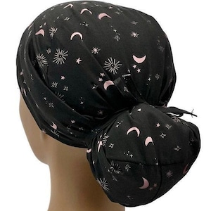 May include: Black scrub hat with a pink and white moon and star pattern. The hat is tied at the back with a bow.