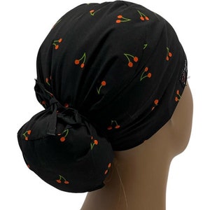 May include: Black scrub hat with a cherry print. The hat has a bun covering in the back.