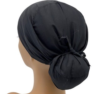 May include: Black surgical scrub hat with a bun cover. The hat is made of a soft, comfortable fabric and has a tie at the back.