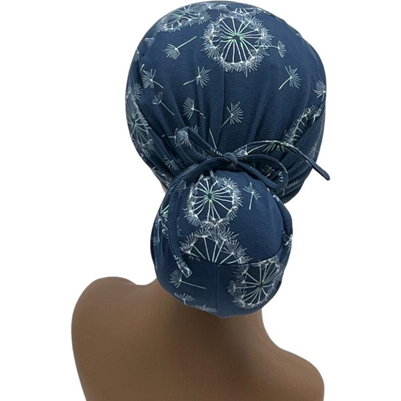 Pode incluir: Uma touca cir&uacute;rgica azul marinho com um padr&atilde;o de dente-de-le&atilde;o branco. A touca &eacute; amarrada na parte de tr&aacute;s e cobre o cabelo. O design inclui uma cobertura de coque. A touca &eacute; feita de tecido macio.