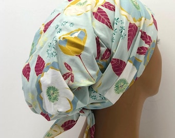 Puede incluir: Un cubrecabezas azul claro con estampado floral en amarillo, blanco y granate. La tela presenta un diseño repetido de flores y hojas. El cubrecabezas está atado en la parte posterior.