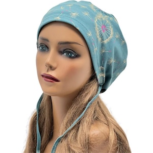 Peut inclure: Un bonnet de couleur sarcelle orn&eacute; d'un motif de pissenlit. Le chapeau pr&eacute;sente un grand motif de pissenlit au centre, avec de plus petites t&ecirc;tes de graines de pissenlit dispers&eacute;es sur le tissu. Le chapeau a des liens sur les c&ocirc;t&eacute;s.