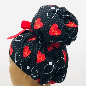 May include: Black scrub hat with a red bow and a pattern of red hearts with EKG lines and white stethoscopes on a black background with white polka dots.
