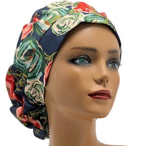 May include: A blue scrub hat with a floral print featuring pink, red, and green roses. The hat is made of a soft, comfortable fabric and is designed to be worn by medical professionals.
