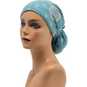 Peut inclure: Un bonnet de chirurgien bleu sarcelle orn&eacute; d'un motif de pissenlit avec des accents roses et blancs. Le bonnet est en tissu doux et poss&egrave;de un dos fronc&eacute; pour un ajustement s&ucirc;r. Con&ccedil;u pour les professionnels de la sant&eacute;.