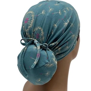 Peut inclure: Bonnet de gommage bleu sarcelle avec un motif de pissenlit blanc et rose. Le bonnet est nou&eacute; en chignon &agrave; l'arri&egrave;re. Le bonnet est en tissu doux et est con&ccedil;u pour couvrir les cheveux.