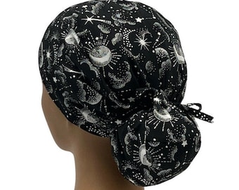 May include: Black scrub hat with a silver and white celestial print featuring moons, stars, and clouds. The hat has a bun tie.