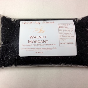 May include: A clear plastic bag filled with dark brown walnut mordant. The label reads "Walnut Mordant Colorant for Organic Pigments" and provides instructions for use. The bag contains 1 lb (453.6 g) of the product.
