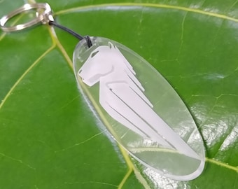 May include: A clear acrylic keychain with a white silhouette of a horse. The keychain is attached to a black cord and a silver key ring.