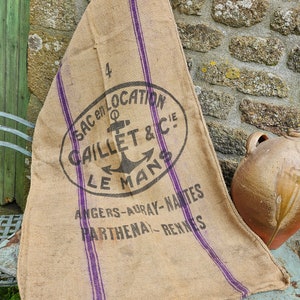 Könnte beinhalten: Ein alter Jutesack mit violetten Streifen und dem Text "SAC en LOCATION CAILLET & CIE LE MANS ANGERS-AURAY-NANTES PARTHENA-RENNES".