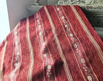 Peut inclure: Un tissu rouge avec des rayures verticales crème et des motifs floraux. Le tissu est texturé et drapé. Le motif floral comprend des fleurs blanches et des feuilles vertes.