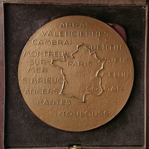 Puede incluir: Una medalla de bronce con un mapa de Francia y los nombres de las ciudades alrededor del per&iacute;metro. Las ciudades que aparecen son: Arras, Valenciennes, Cambrai, St Quentin, Montreuil-sur-Mer, Par&iacute;s, Amiens, Melun, Colmar, Angers, Nantes y Toulouse.
