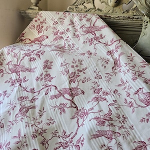 Könnte beinhalten: Ein Textilstoff mit einem sich wiederholenden Toile-Muster in tiefem Magenta auf cremeweißem Grund. Das Design zeigt Vögel, die auf blühenden Zweigen mit Blättern und Blüten sitzen, überlagert von einer dezenten vertikalen Streifenstruktur.