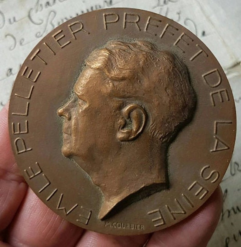 Puede incluir: Una medalla de bronce con la inscripci&oacute;n "Emile Pelletier Prefet de la Seine" y el nombre "A. Courbier" en la parte inferior.