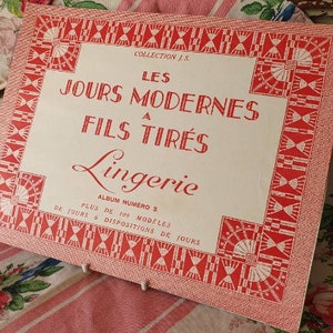 May include: A vintage white and red album cover with the title "LES JOURS MODERNES A FILS TIRÉS Lingerie" and the text "ALBUM NUMERO 3 PLUS DE 100 MODELES DE JOURS & DISPOSITIONS DE JOURS".