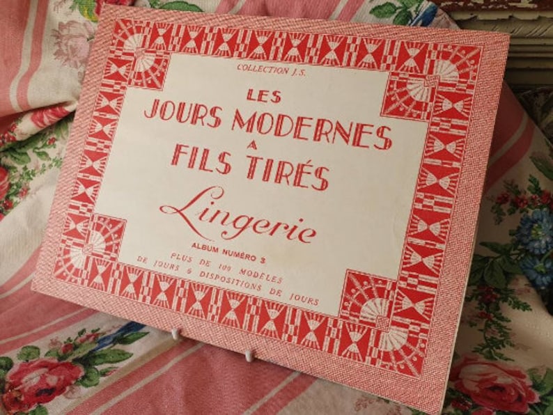 Peut inclure: Une couverture d'album vintage blanche et rouge avec le titre "LES JOURS MODERNES A FILS TIR&Eacute;S Lingerie" et le texte "ALBUM NUMERO 3 PLUS DE 100 MODELES DE JOURS & DISPOSITIONS DE JOURS".