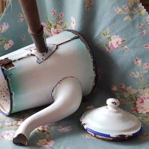 May include: A vintage enamelware coffee pot with a blue and white design. The pot has a long spout and a wooden handle. The lid is also enamelware and has a blue rim.