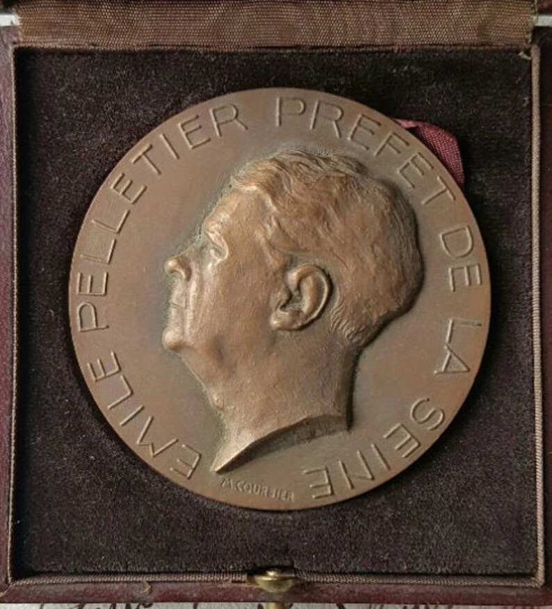 Puede incluir: Una medalla de bronce con un retrato de perfil de Emile Peltier, Prefecto del Sena. La medalla est&aacute; inscrita "Emile Peltier Prefecto del Sena" y "A. Coursier".