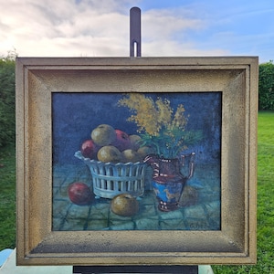 Può includere: Dipinto a olio di natura morta con un cesto bianco pieno di mele e pere, una brocca blu e rossa e fiori gialli. L'opera è in una cornice dorata.