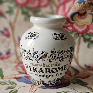 Puede incluir: Tarro de cerámica blanco con un diseño floral y el texto "moutarde Pikarom au vinaigre fin".