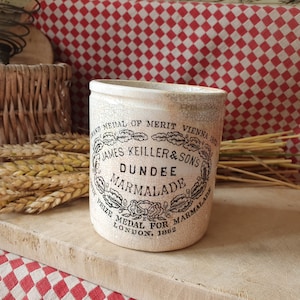May include: A vintage white ceramic jar with black lettering that reads "AND MEDAL OF MERIT VIENNA 1862 JAMES KEILLER & SONS DUNDEE MARMALADE PRIZE MEDAL FOR MARMALADE LONDON. 1862".