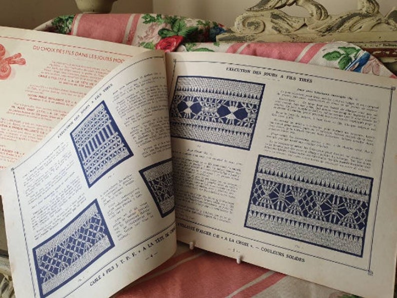 Peut inclure: Un livre vintage avec des instructions pour "Ex&eacute;cution des jours &agrave; fils tir&eacute;s". Le livre pr&eacute;sente des illustrations en noir et blanc de diff&eacute;rents points et motifs. Le texte comprend la phrase fran&ccedil;aise "Ex&eacute;cution des jours &agrave; fils tir&eacute;s" et la phrase anglaise "Drawn Thread Work".