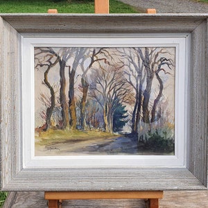 May include: A framed watercolor painting depicting a woodland scene with a path leading through a grove of trees. The trees are bare and the sky is a light blue. The painting is in a simple gray frame.