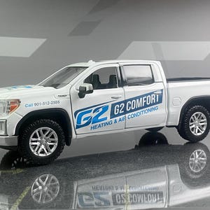 May include: A white GMC pickup truck model with black wheels. The truck has the logo "G2 COMFORT HEATING & AIR CONDITIONING" in blue on the side. The phone number 901-512-2555 is also visible on the truck.
