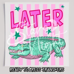 May include: A graphic design featuring a green alligator with a pink underbelly, positioned below the pink text LATER. The background consists of vertical pink and white stripes accented with small teal stars. The text READY TO PRESS TRANSFERS appears below.