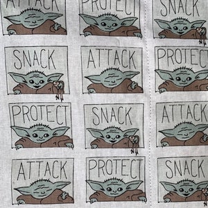 Pu&ograve; includere: Tessuto bianco con un motivo ripetuto di un personaggio dei cartoni animati in una veste marrone. Ogni personaggio &egrave; incorniciato in un riquadro grigio con le parole "SNACK", "ATTACK" e "PROTECT" in testo nero. Il personaggio tiene in mano una piccola creatura.