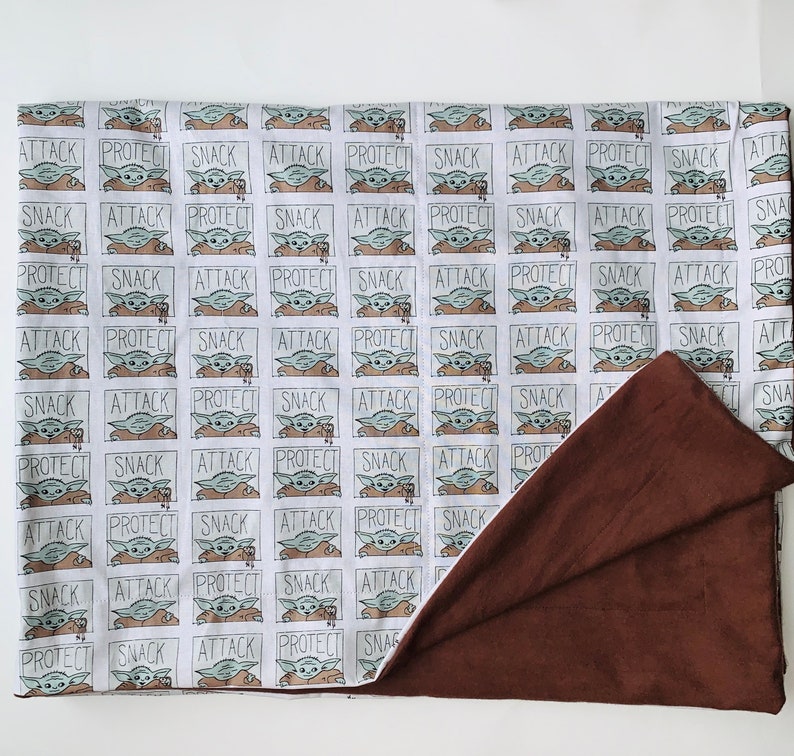 Pu&ograve; includere: Una coperta reversibile con un motivo ripetuto di un personaggio dei cartoni animati e le parole "ATTACK", "PROTECT" e "SNACK". Un lato &egrave; bianco a fantasia, l'altro &egrave; marrone tinta unita. Adatta per letto o divano.