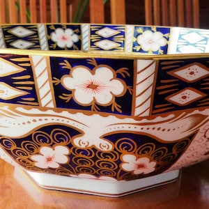 May include: A large, octagonal, porcelain bowl with a blue and gold floral pattern. The bowl is decorated with a repeating pattern of flowers, leaves, and geometric shapes.