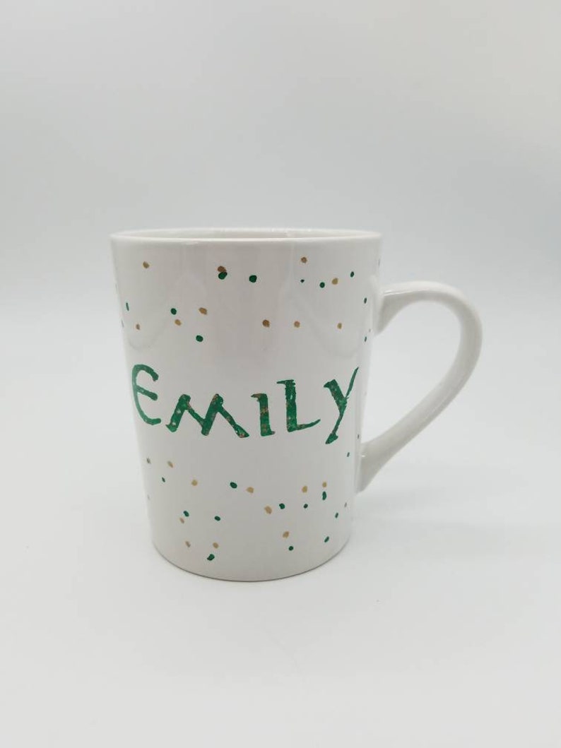 May include: White ceramic mug with a green and gold confetti pattern and the name "Emily" written in green.